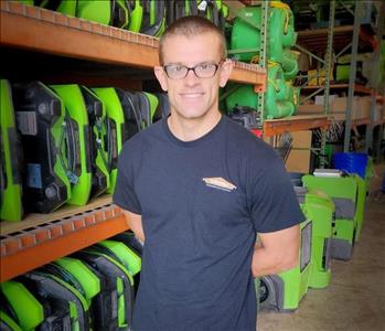 Man is standing in front of a shelf of green air mover fans